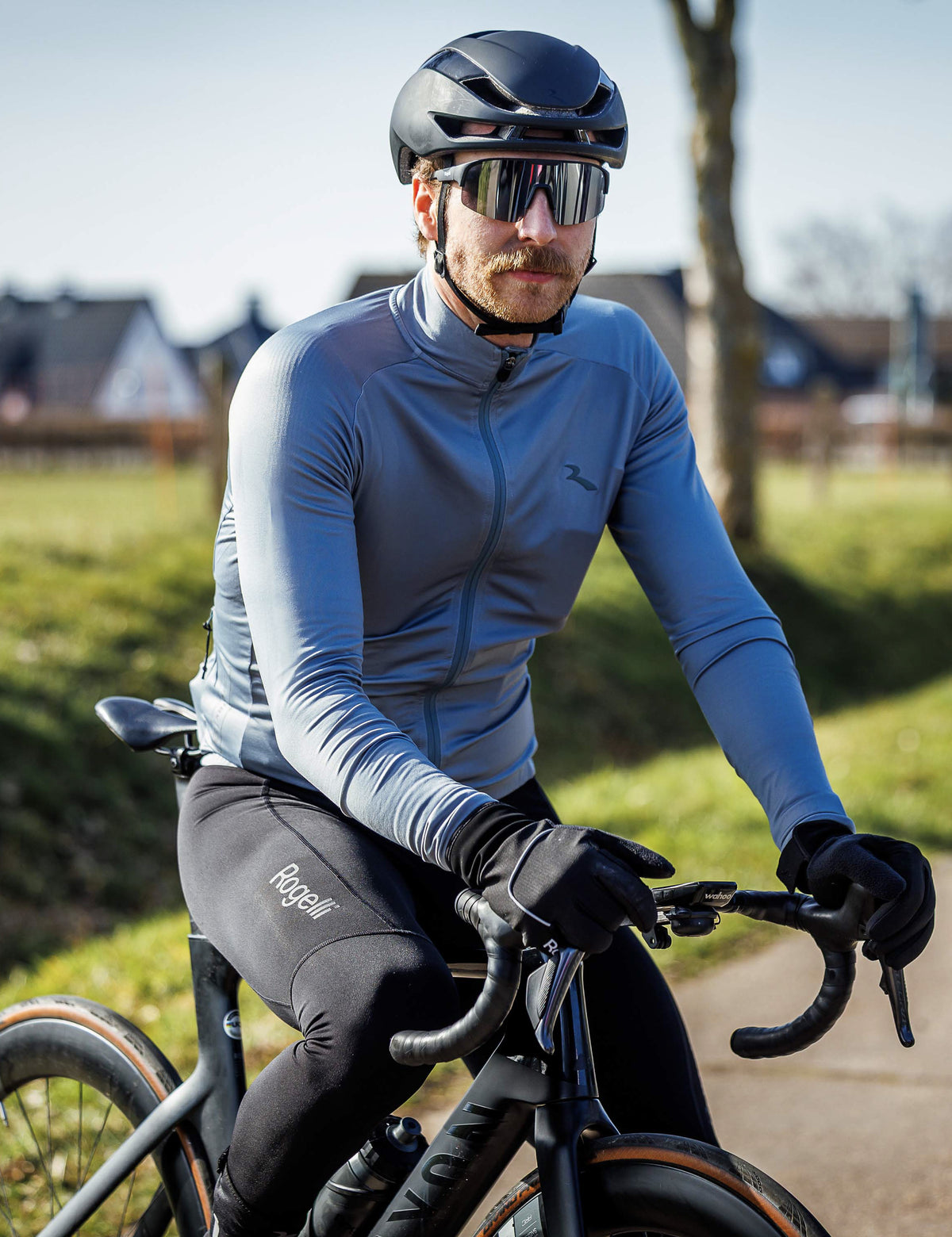 Man in zwarte Rogelli Essential bibtight heren tijdens een rit op de racefiets in koel weer.