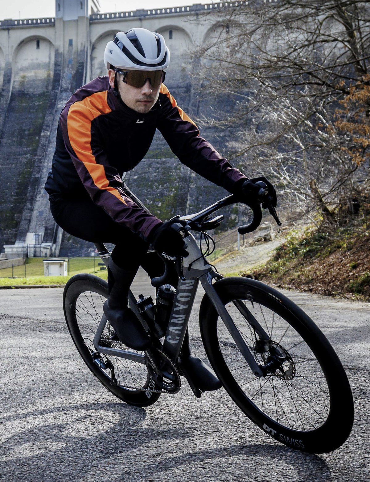 Man in zwart bordeaux oranje Rogelli Freeze winter fietsjack heren tijdens een rit op de racefiets in koud weer.