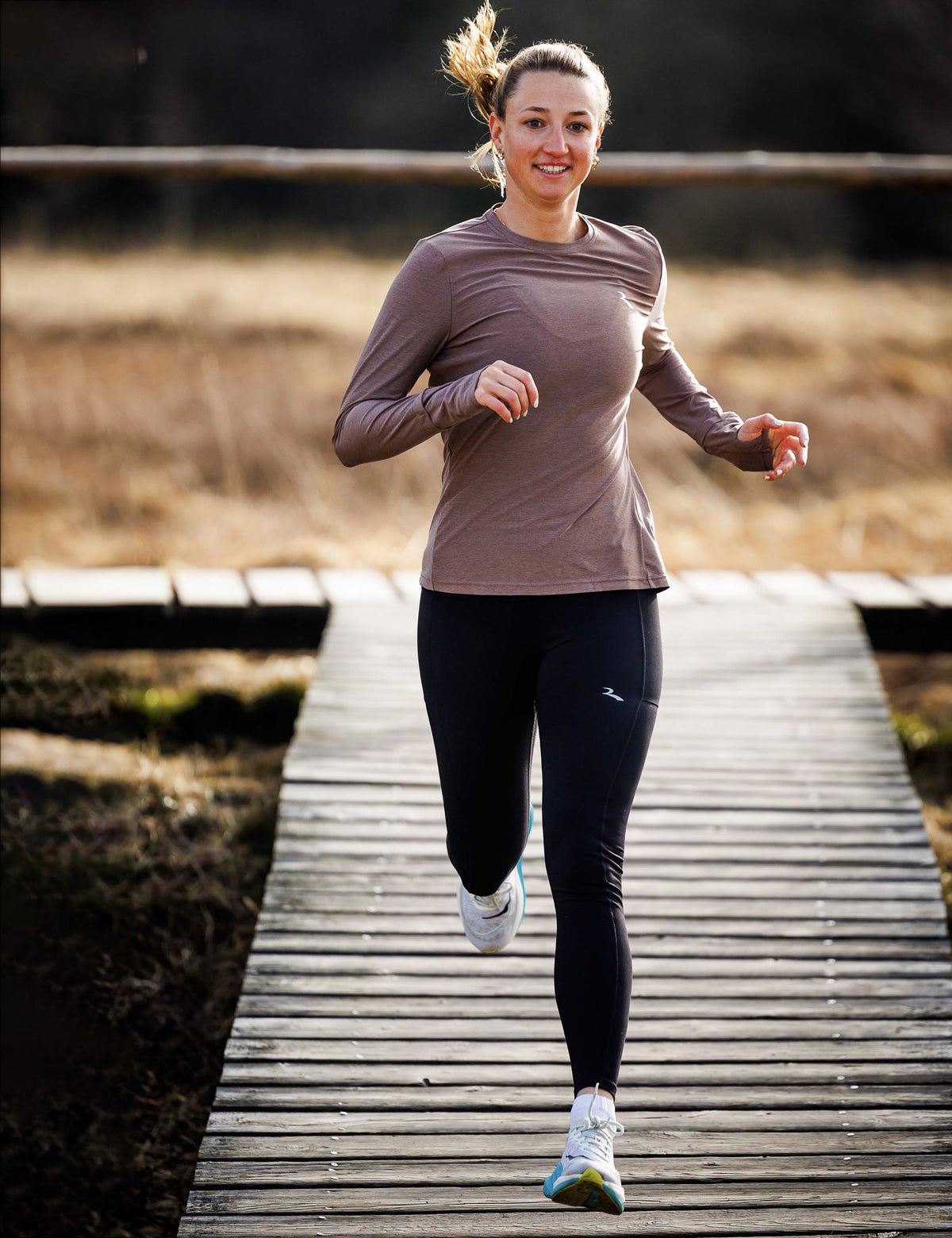 Vrouw in zwarte Rogelli Essential hardloopbroek dames tijdens het hardlopen in de buitenlucht.