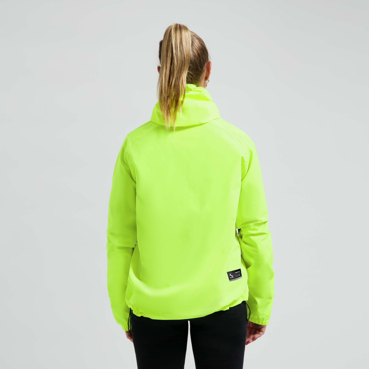 Rogelli Core Commuter regenjas unisex fluor gedragen door vrouw achterkant.