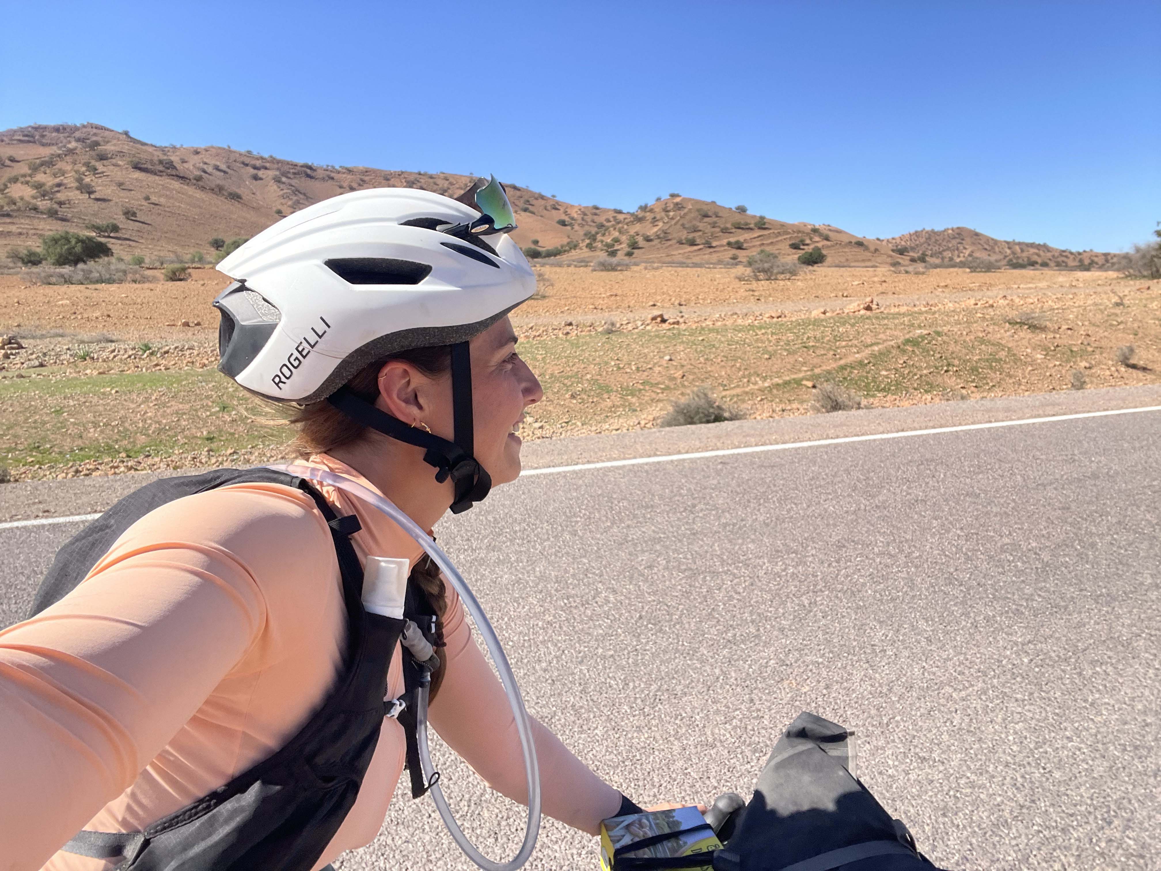Vrouw tijdens een bikepacking tocht in Marokko op een stille weg door berglandschap.