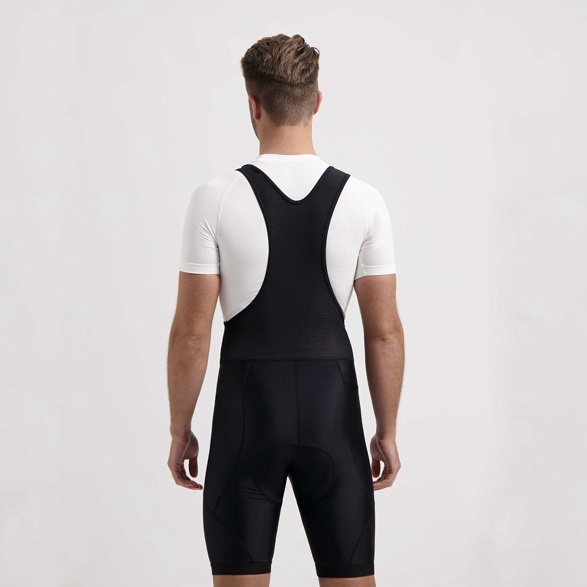 Achterzijde fietser in zwarte fietsbroek met ademende mesh bretels, ideaal bij warm weer.