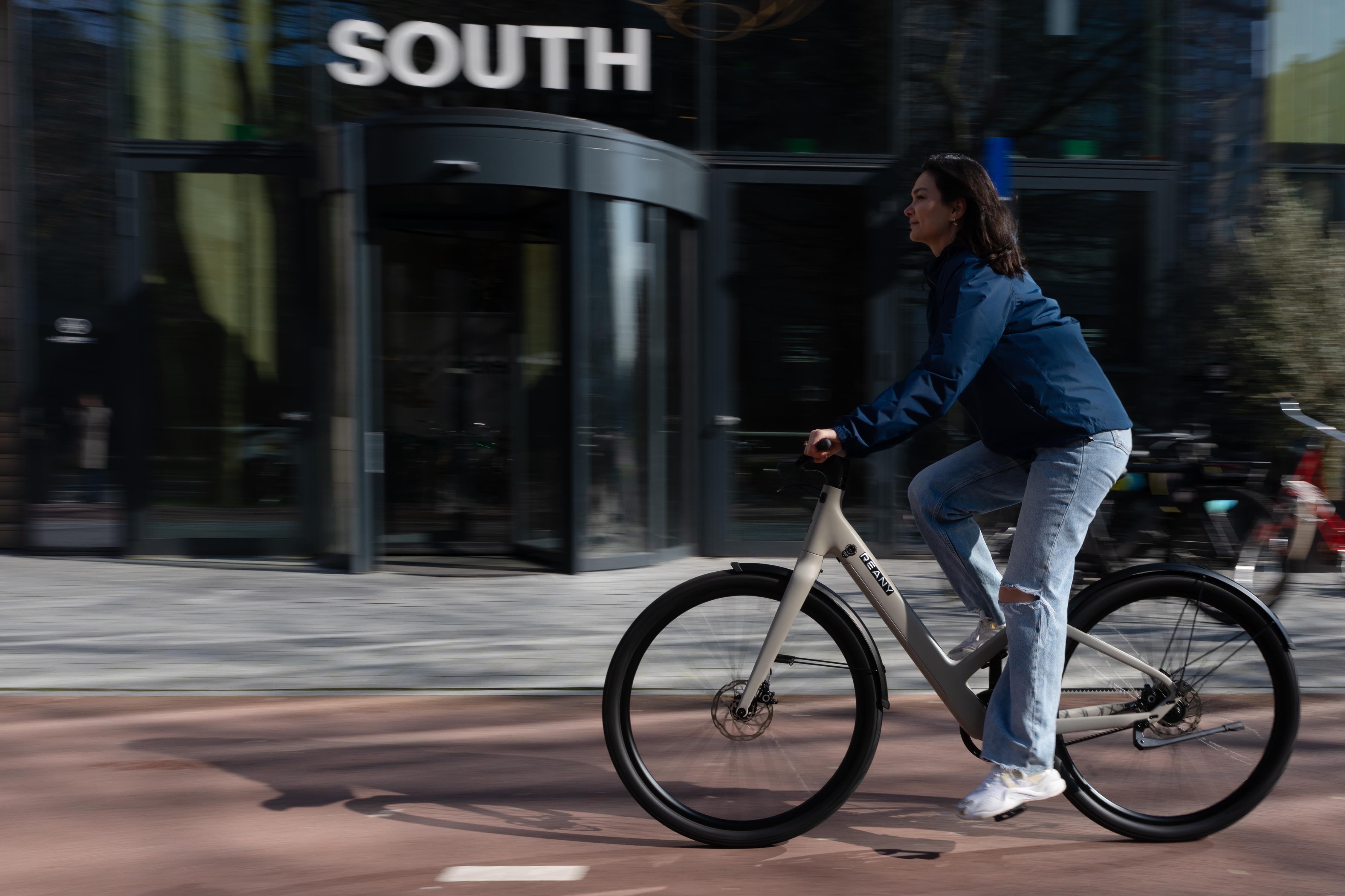 Fietser fietsend door de stad met het commuter core regenjack blauw aan.