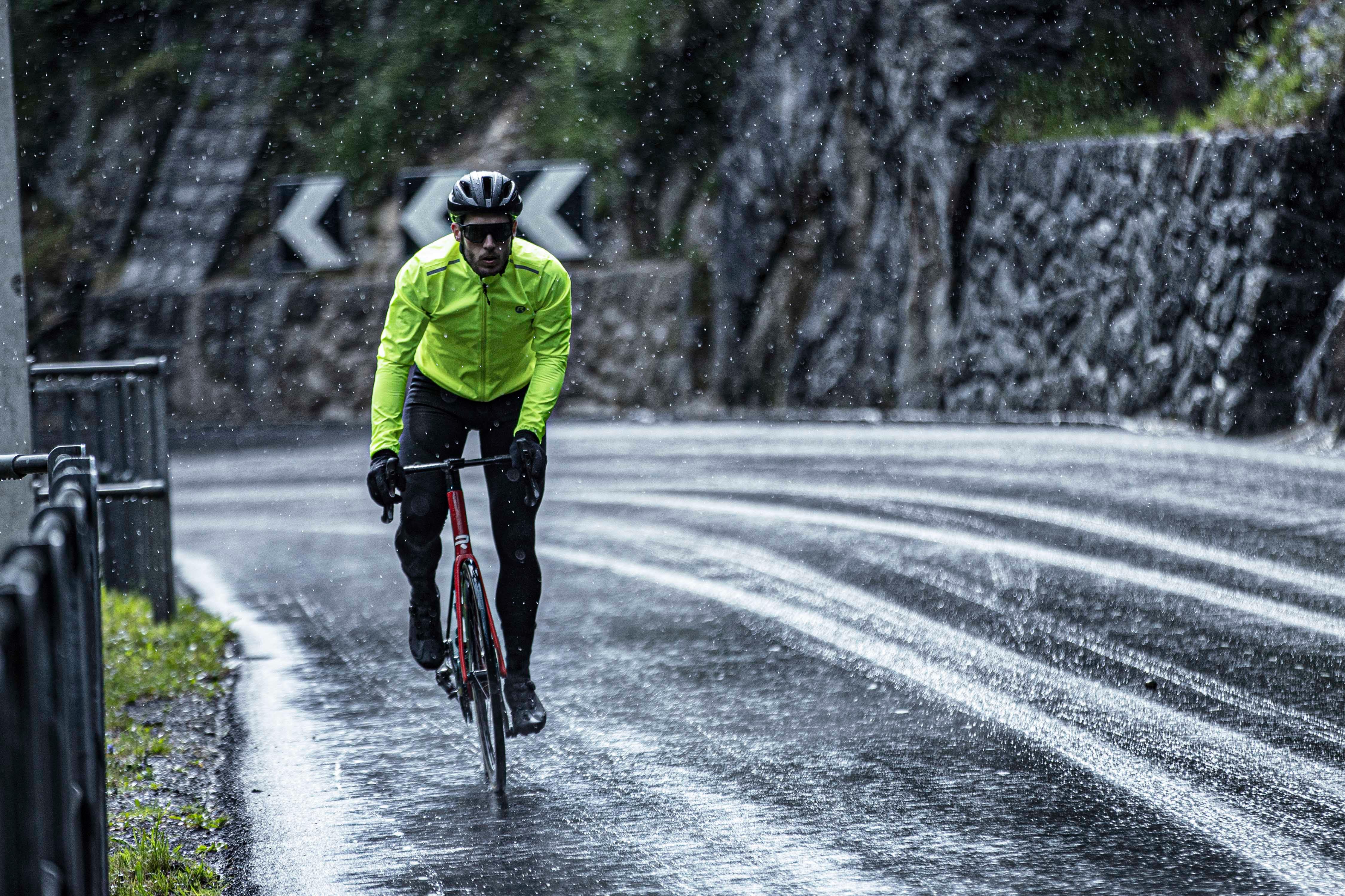 Wielrenner in Rogelli regenjack tijdens een rit in de regen op natte weg.