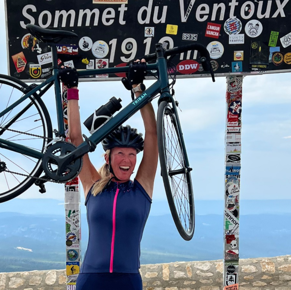 Frouke lifting her bike at the Sommet du Ventoux sign after climbing as a beginner cyclist.