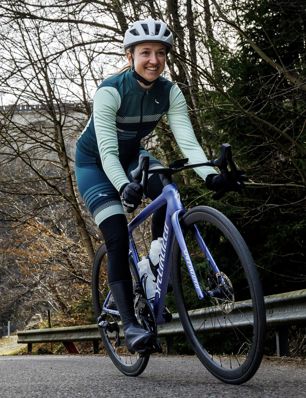 Vrouw in Rogelli Stryde bibtight dames in pine-limoen tijdens een rit op de racefiets in een bosrijke omgeving.