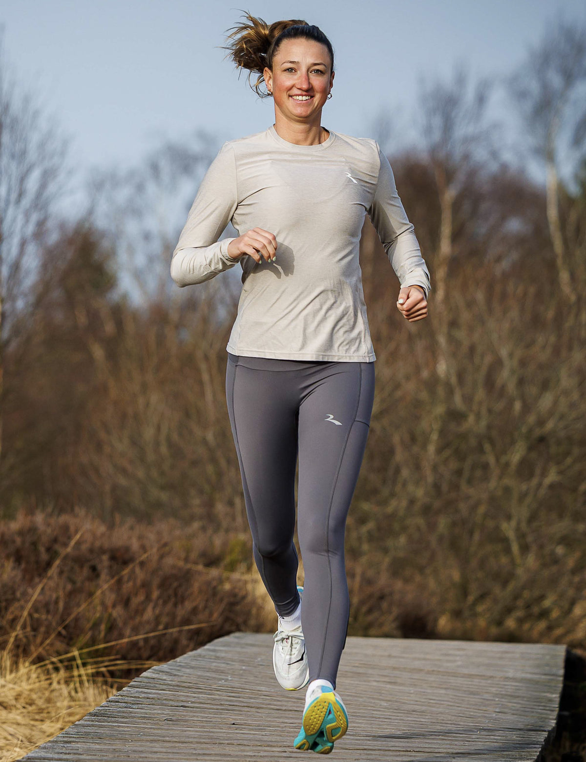 Vrouw in grijze Rogelli Essential hardlooptight dames tijdens het hardlopen in de buitenlucht.