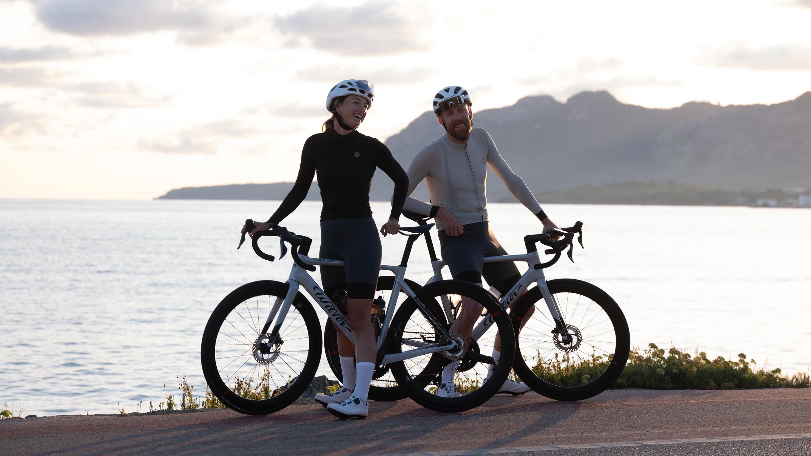 Man en vrouw in Rogelli fietsshirts met lange mouwen tijdens een fietstocht langs de kust.
