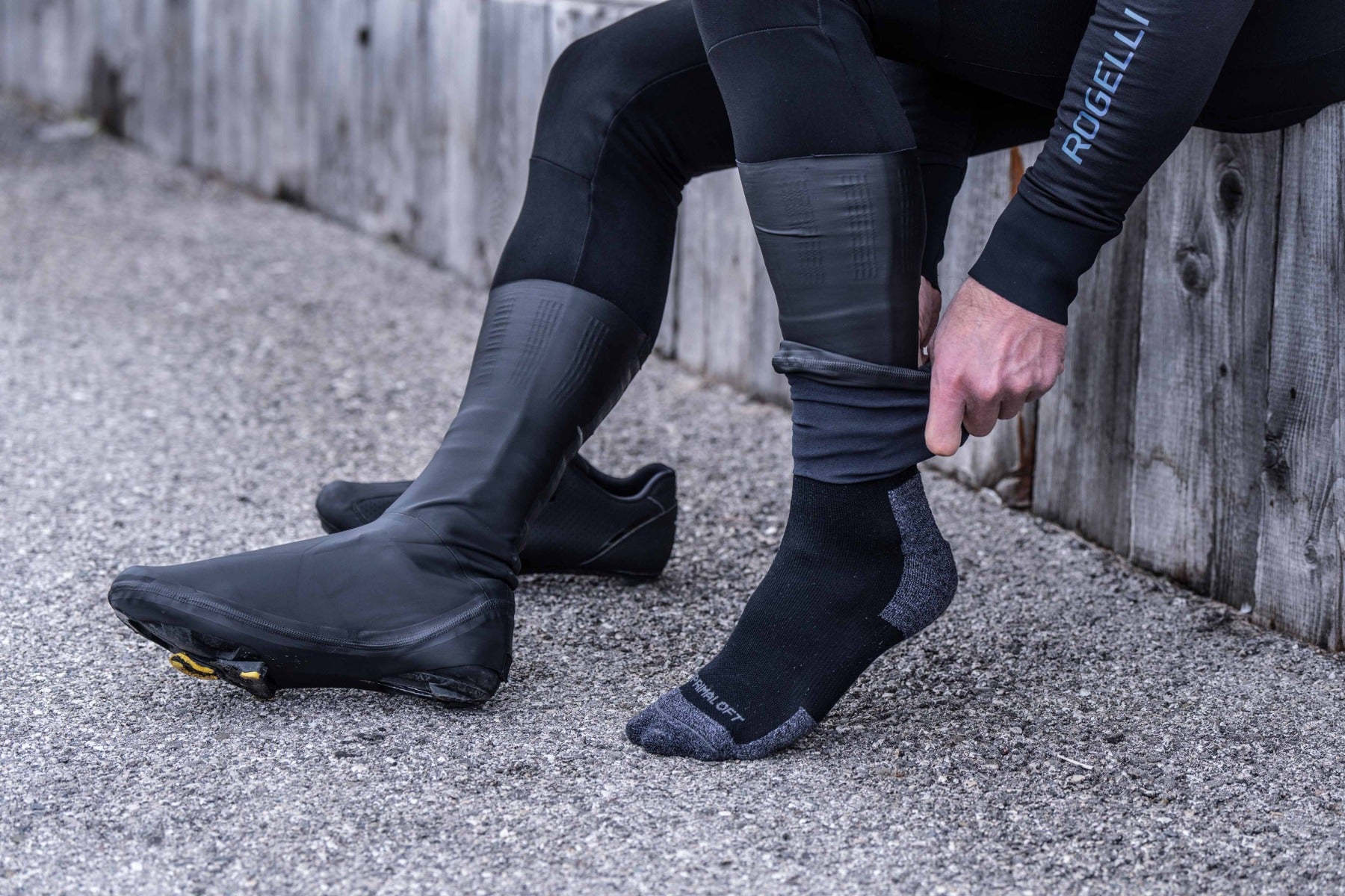 Fietser trekt overschoenen tot over de enkel aan – stap 2 in stappenplan overschoenen aantrekken wielrennen.