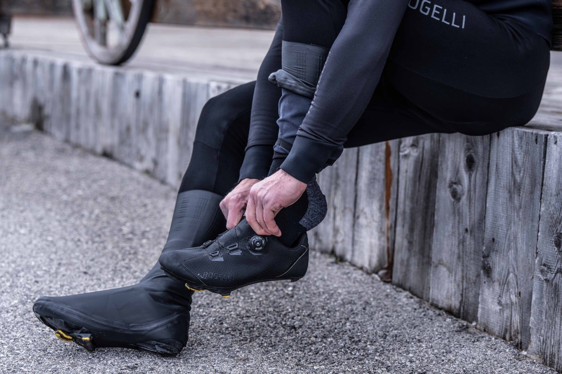 Fietser trekt fietsschoenen aan nadat overschoenen tot de enkel zitten – stap 3 overschoenen aantrekken wielrennen.