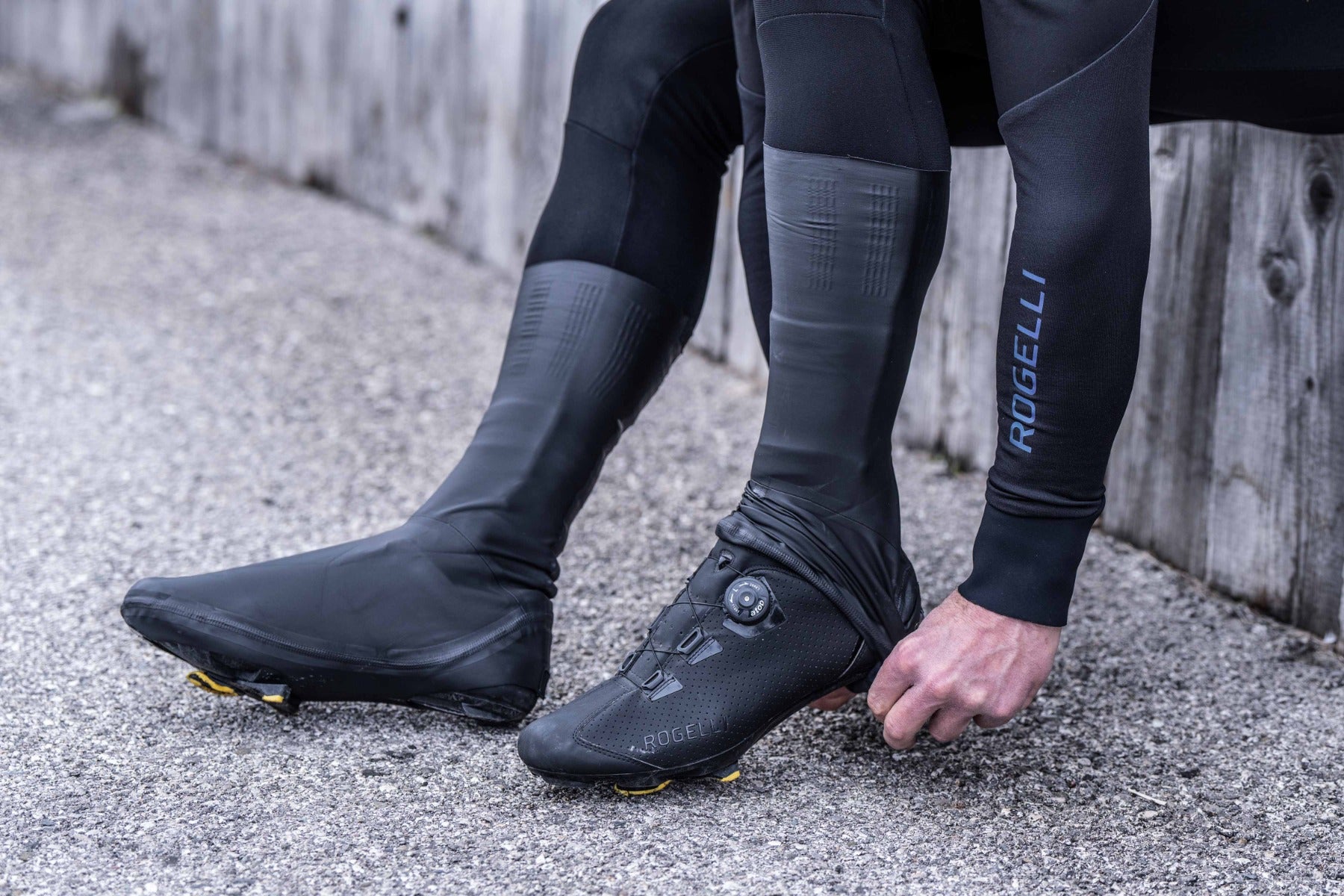 Fietser trekt overschoen volledig over fietsschoen – overschoenen wielrennen klaar voor vertrek.
