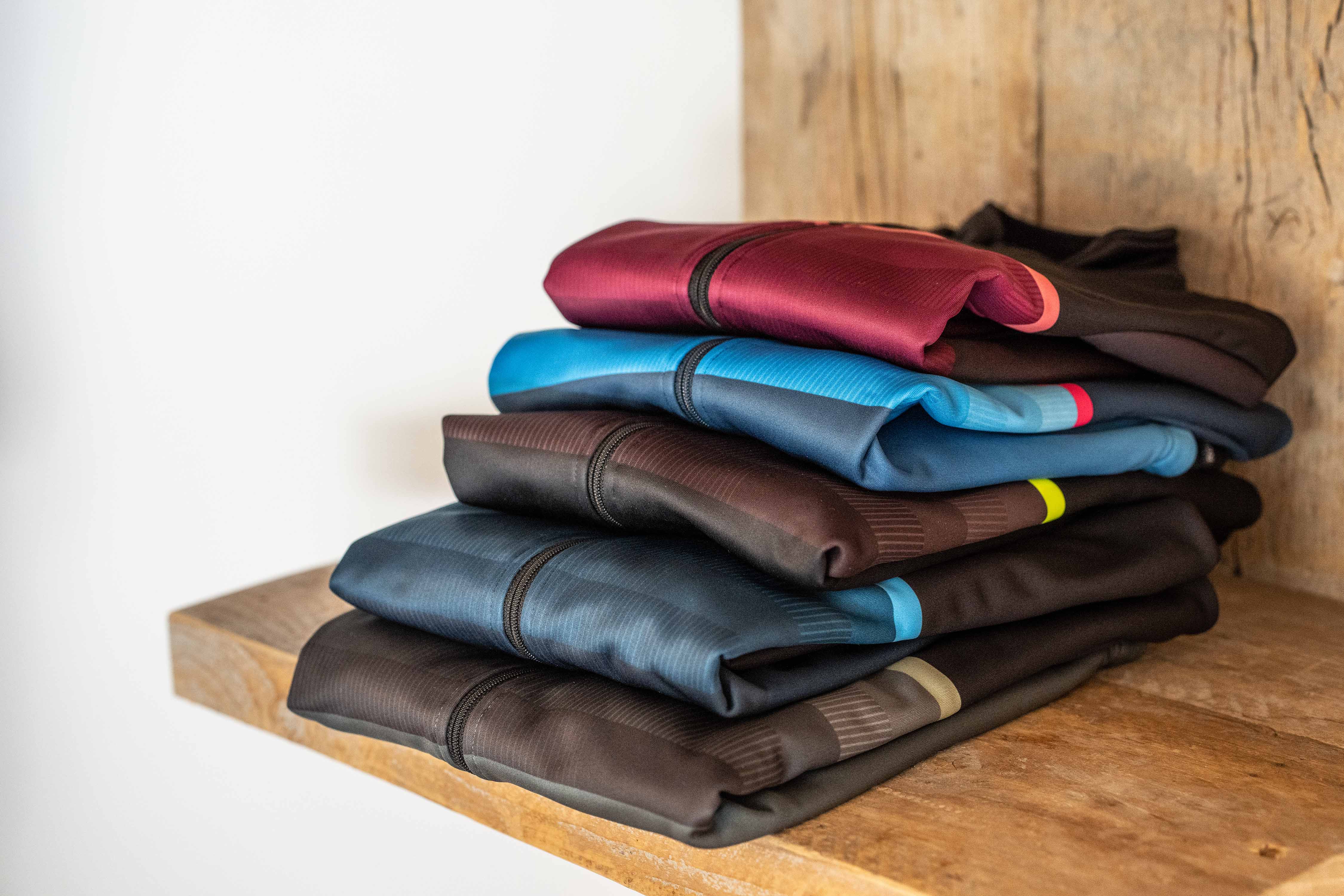 Foto van stapel fietsshirts op een houten plank.