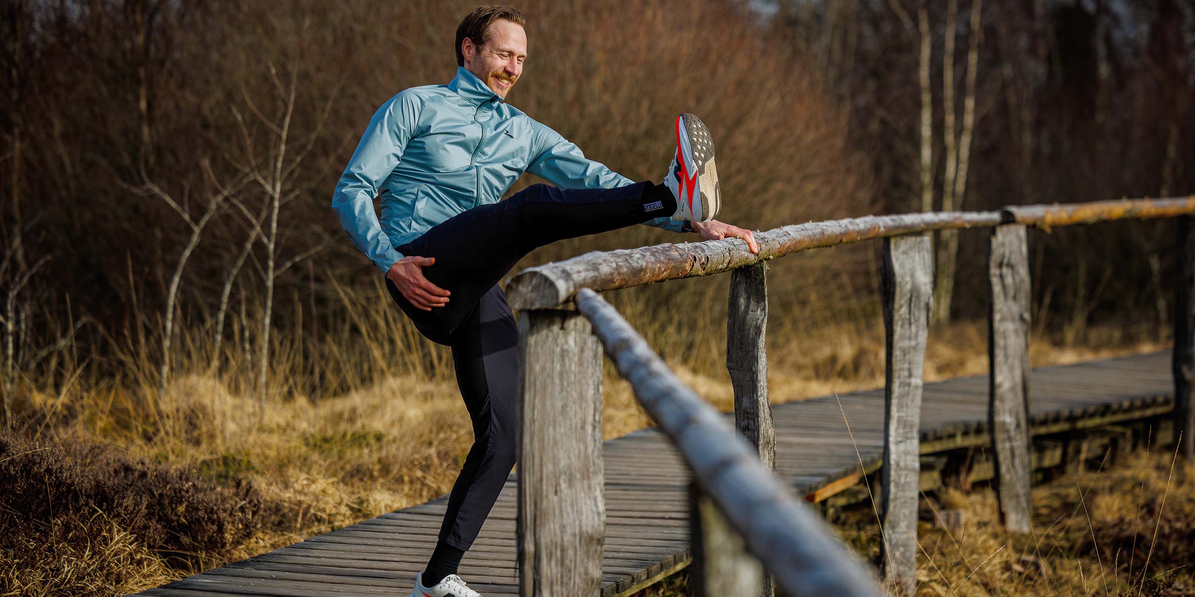 Man in Rogelli hardloopbroek heren rekt zijn benen voor een hardloopsessie.