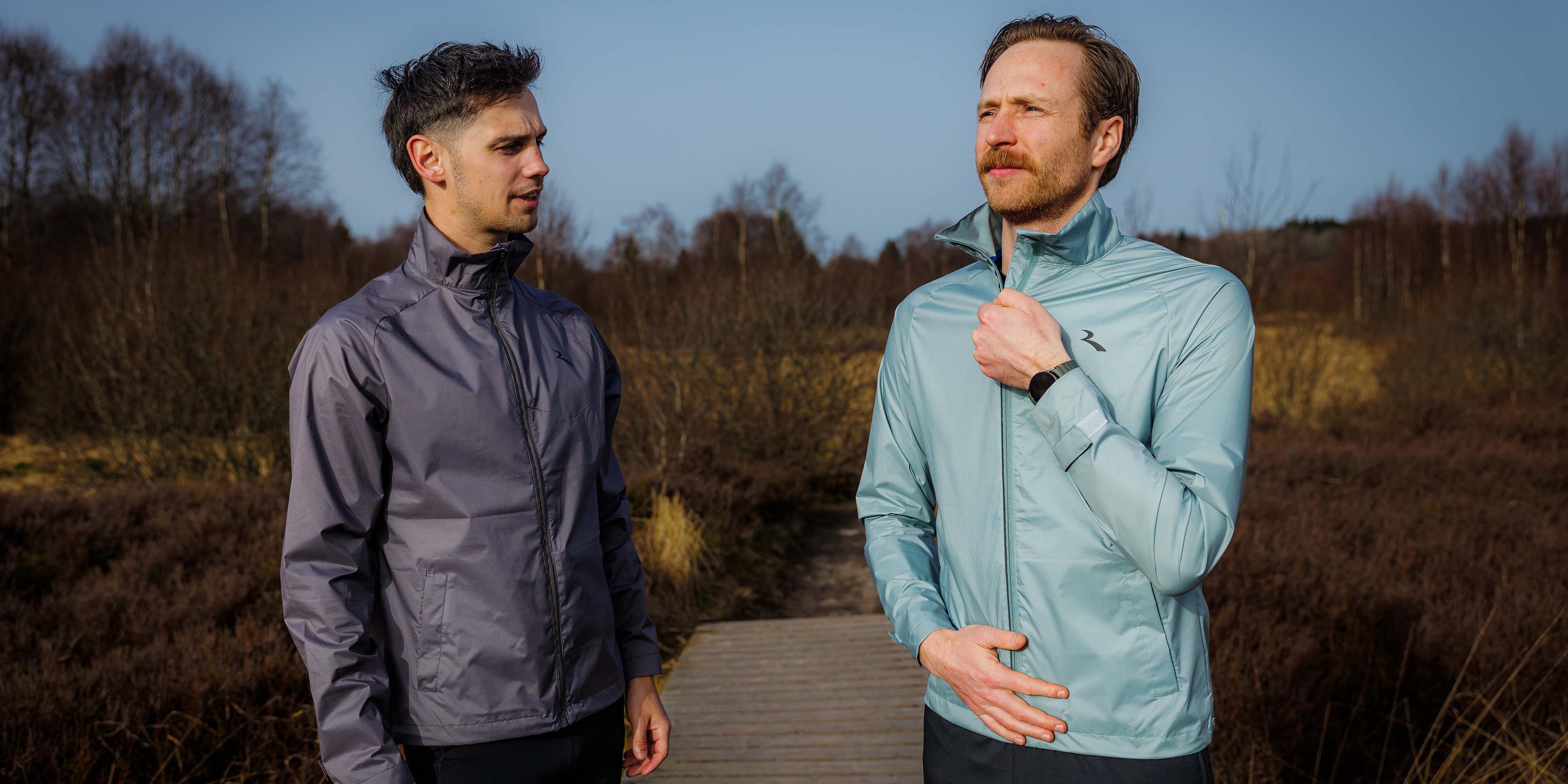 Twee mannen in Rogelli hardloopkleding heren dragen een hardloopjack tijdens een run in de buitenlucht.