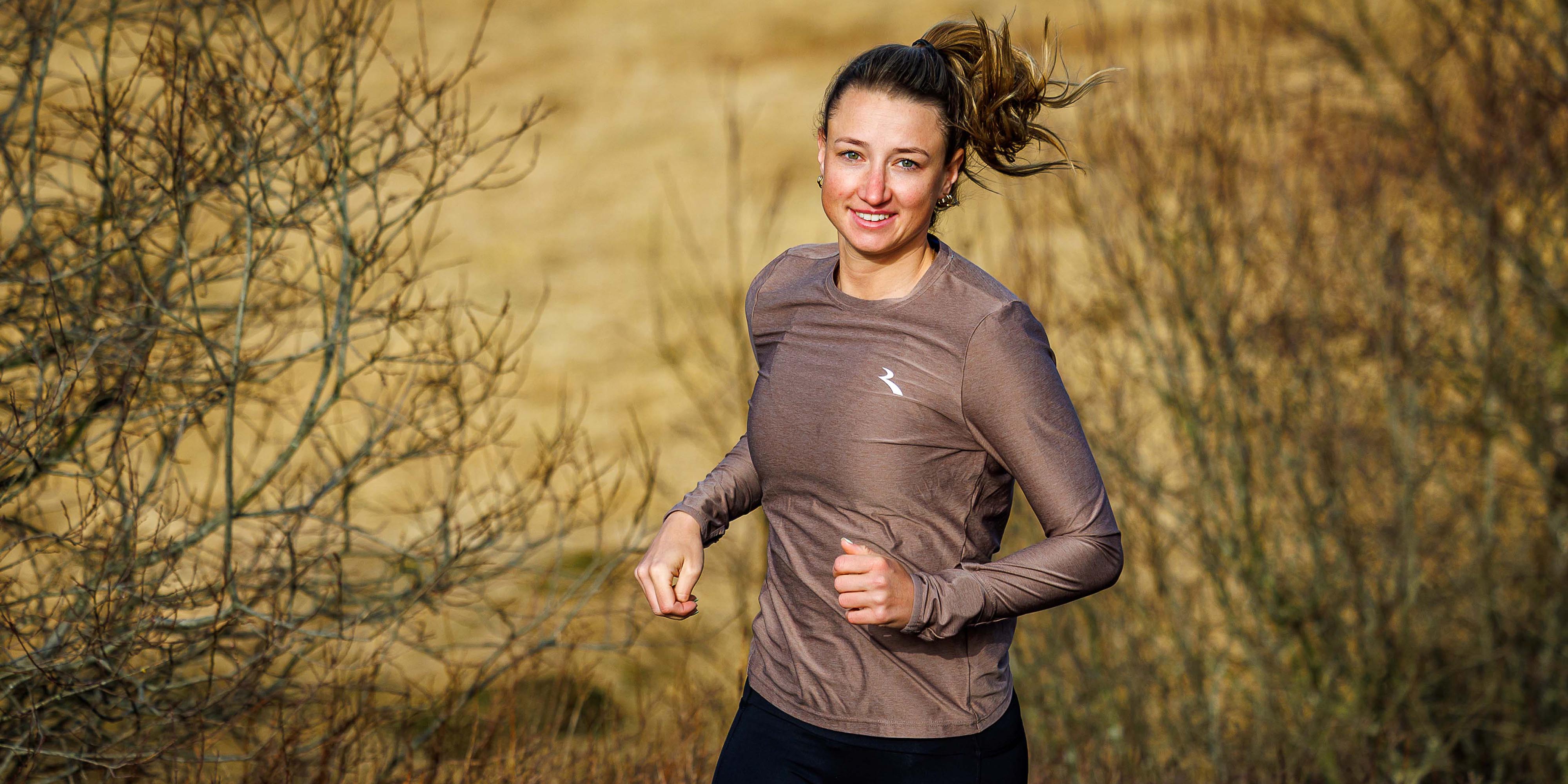 Vrouw in Rogelli hardloopshirt dames met lange mouwen tijdens het hardlopen in de buitenlucht.