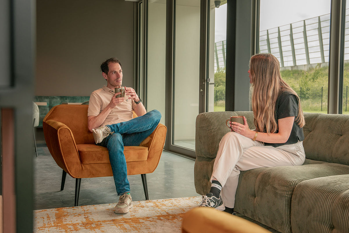 Twee collega’s praten ontspannen met een kop koffie in de zithoek van het Rogelli-kantoor in Breda.
