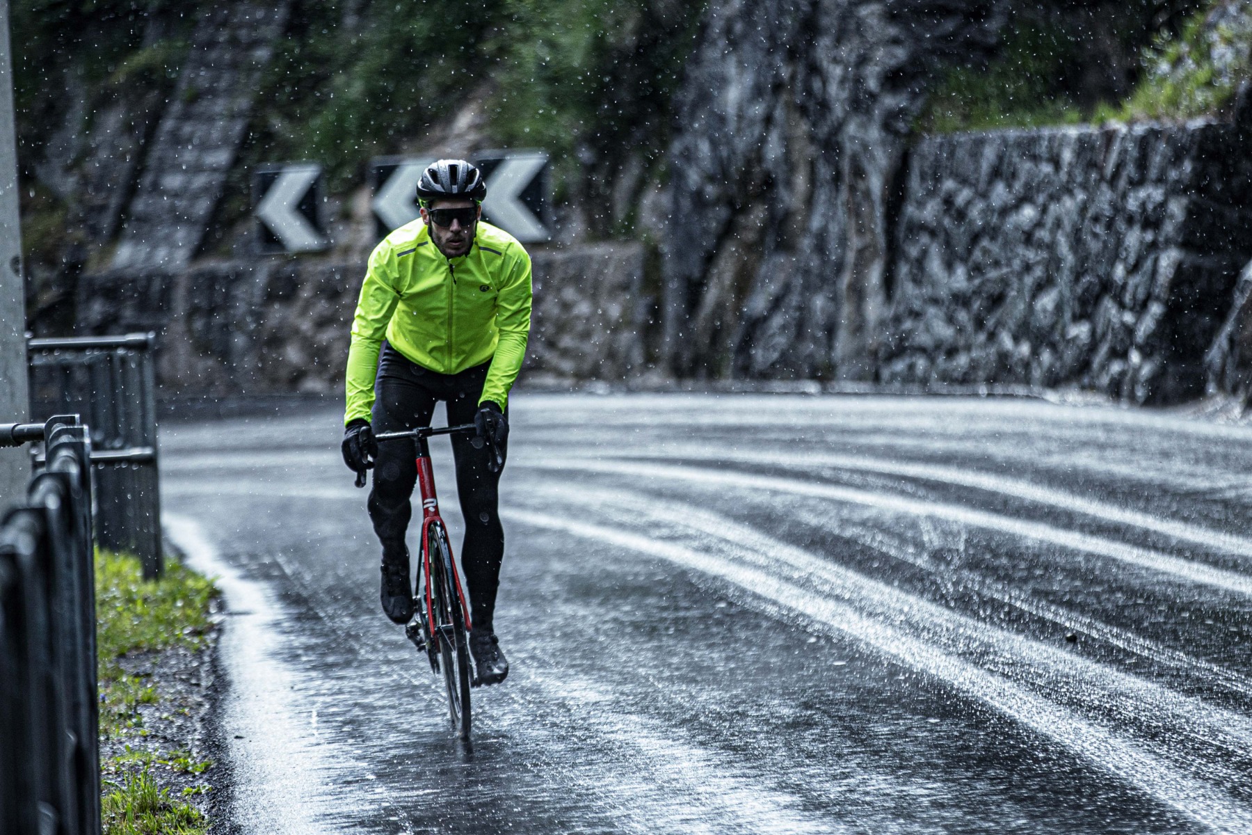 Wielrenner in geel Rogelli regenjack fietst droog door een regenbui.