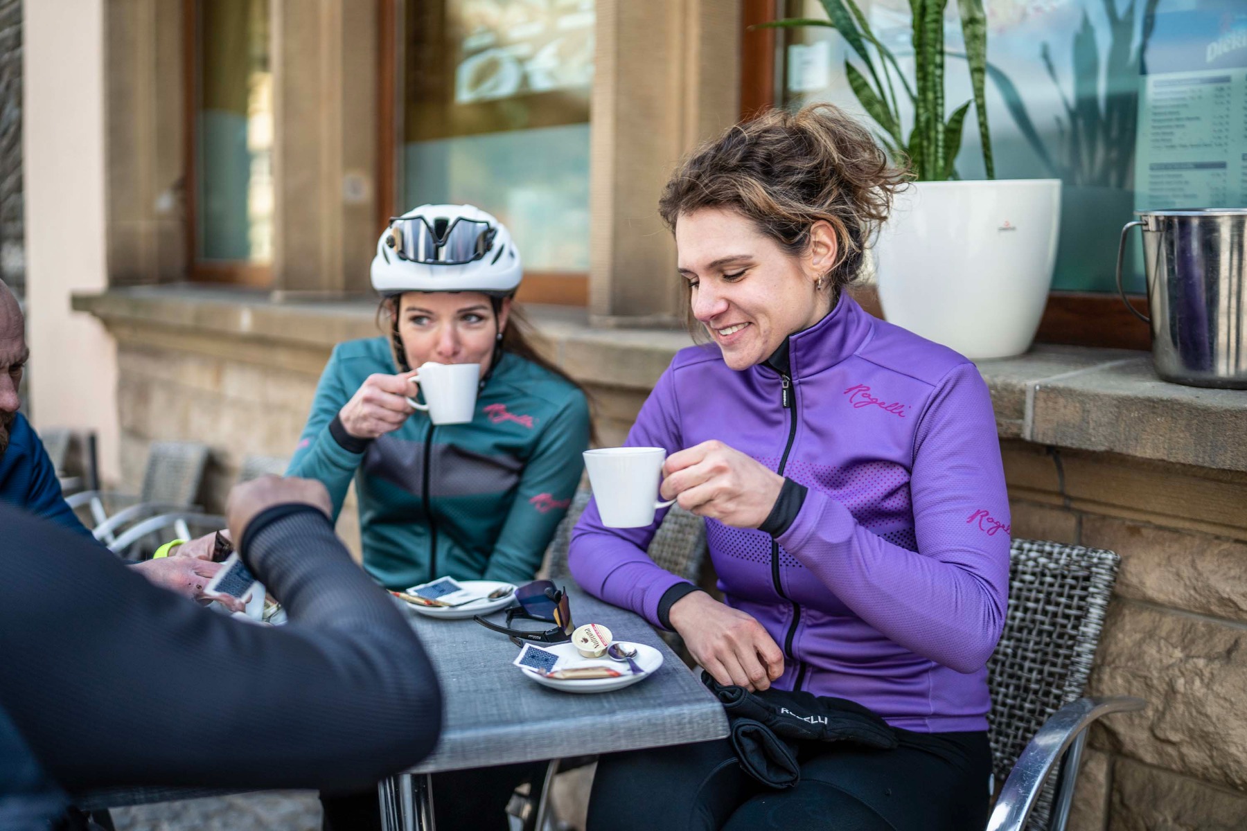 Twee vrouwen gekleed in comfortabele Rogelli fietskleding genieten van een heerlijke warme chocolademelk met slagroom, een welverdiende traktatie na een actieve rit.