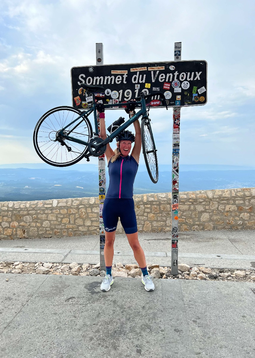 Met een gevoel van triomf poseren twee wielrenners met hun fietsen in de lucht, vierend na het bereiken van de top van Mont Ventoux. Een ongelooflijke prestatie!