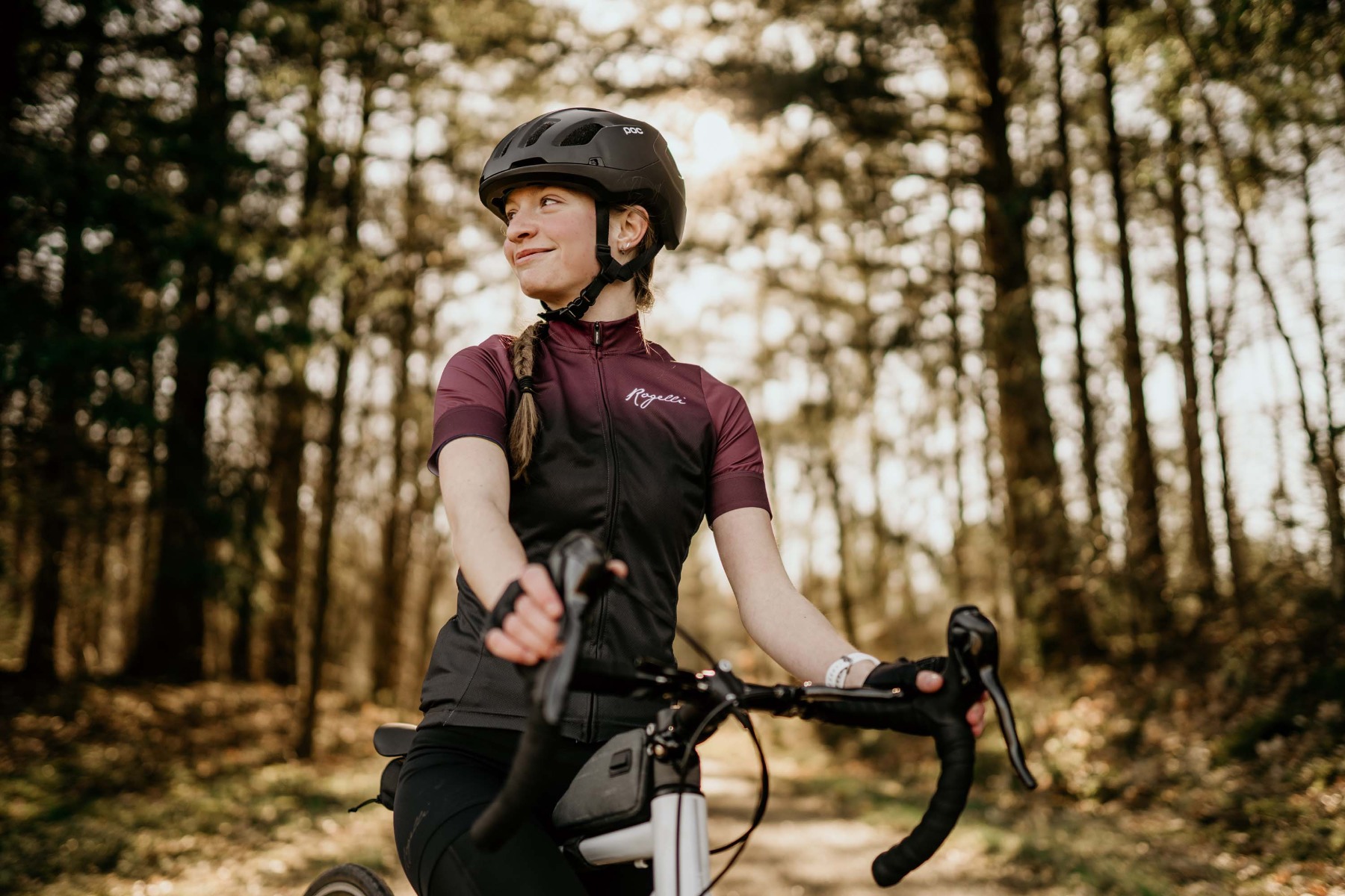 Een vrouwelijke fietser geniet van een rustige rit door het bos, omringd door de prachtige natuur, gekleed in Rogelli fietskleding.