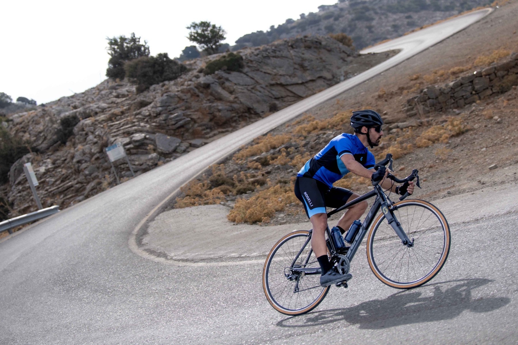 Ein Radsportler fährt auf der Insel Kreta mit Rogelli-Radbekleidung einen Berg hinunter