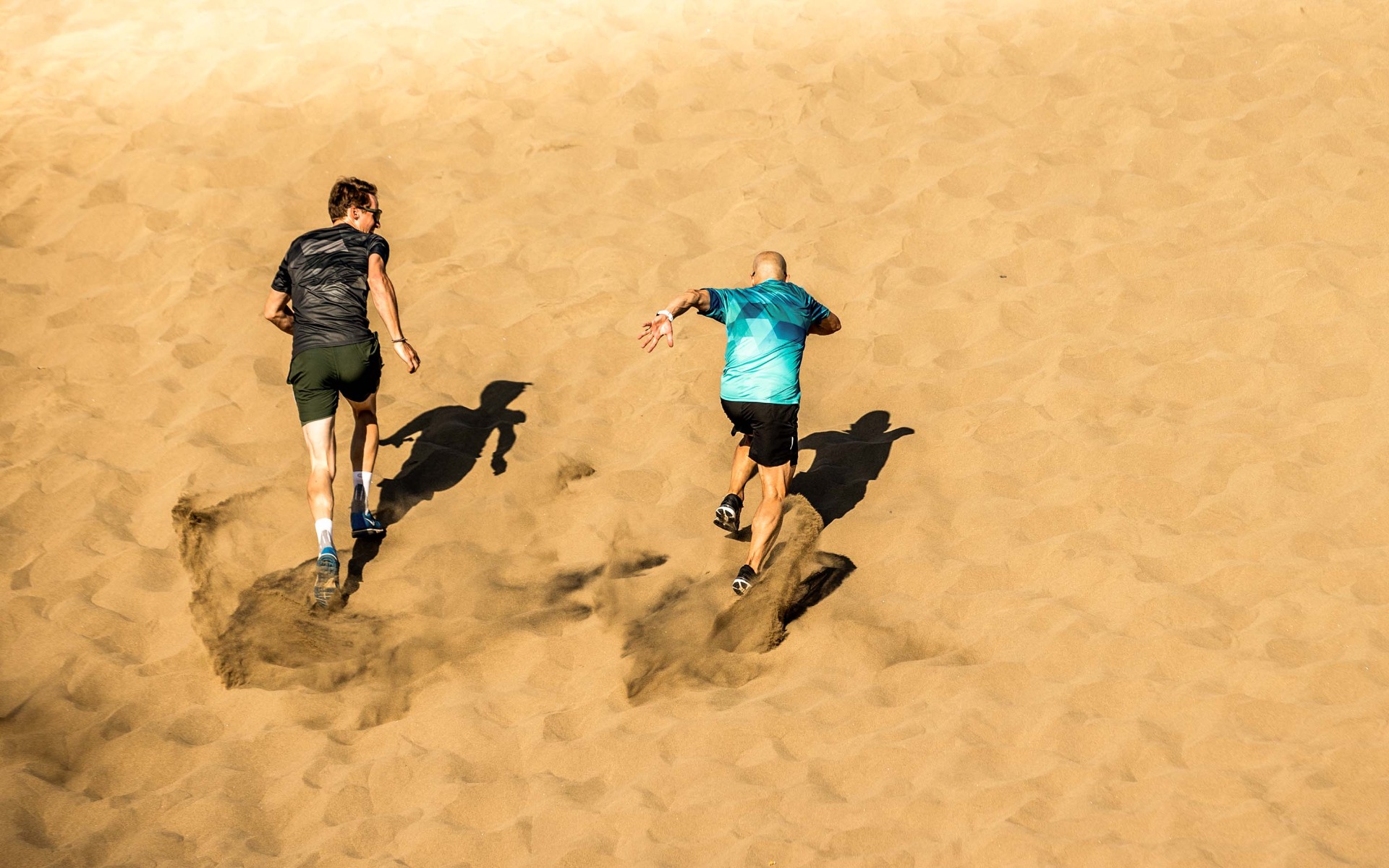 Hardlopers lachen en hebben plezier tijdens het hardlopen op het strand. Rogelli hardloopkleding zorgt voor comfort en flexibiliteit.