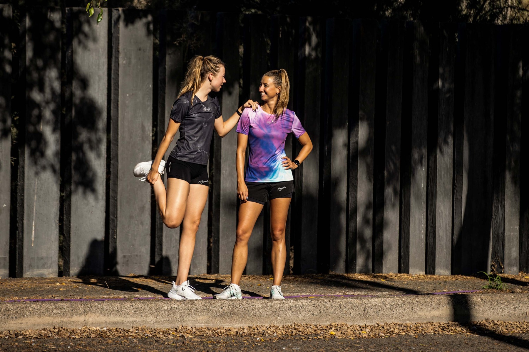 Twee dames in Rogelli hardloopkleding doen rekoefeningen voordat ze gaan hardlopen.
