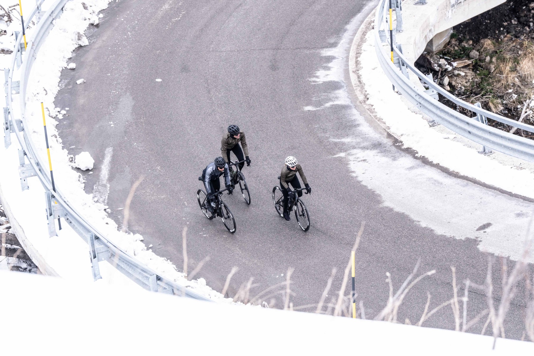 Winterse groepsrit: Twee mannen en één vrouw fietsen in Rogelli fietskleding op besneeuwde weg.