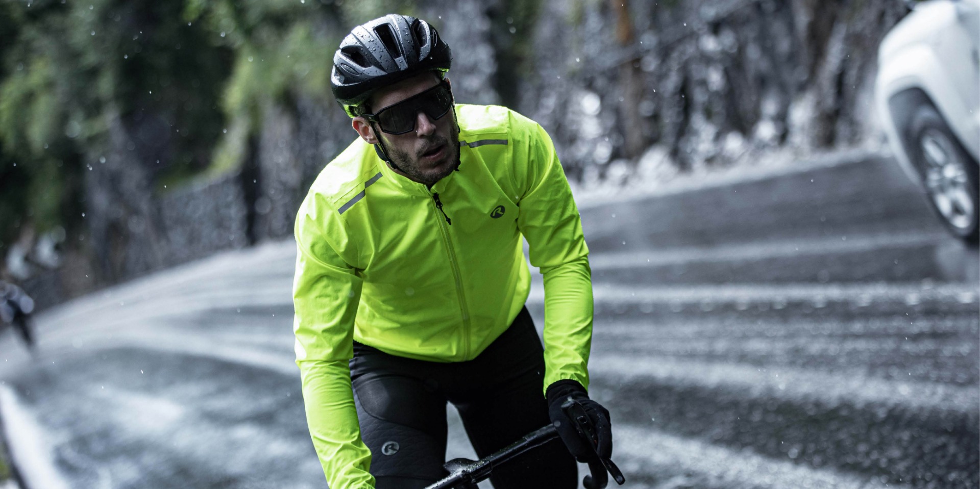 Male cyclist in a striking fluorescent Rogelli rain jacket, enjoying the ride in the rain