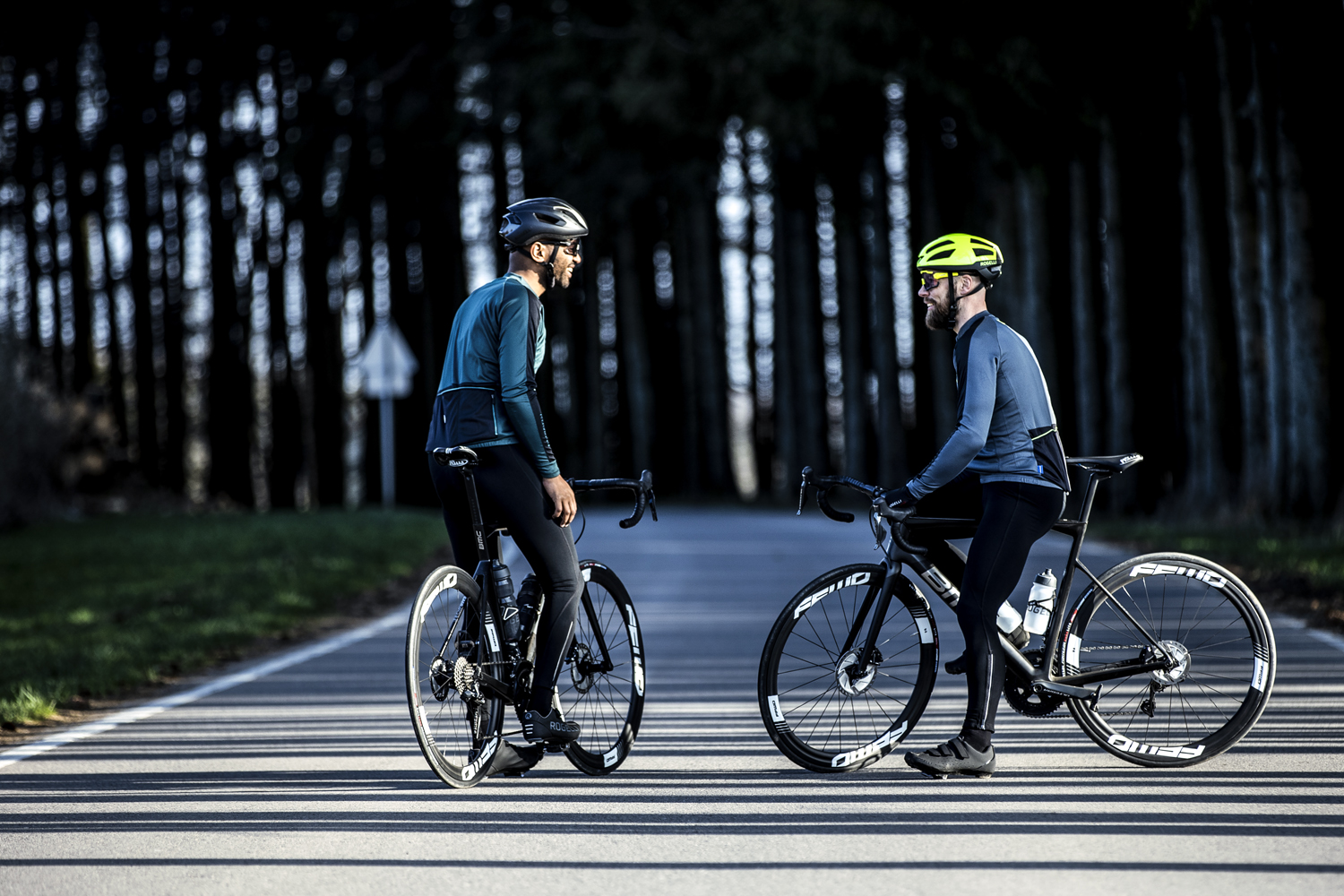 Twee mannelijke wielrenners maken een praatje terwijl ze genieten van een pauze tijdens hun rit.